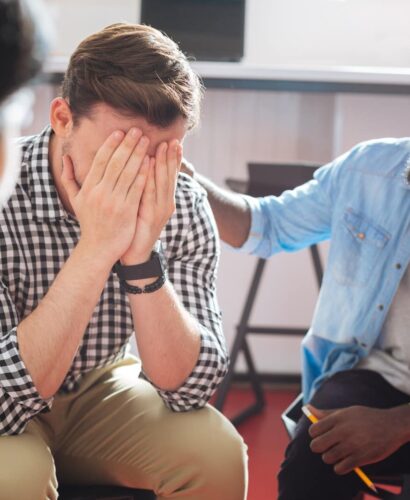 Comforting. Reliable kind black man putting his hand on the shoulder of a crying person while talking to him